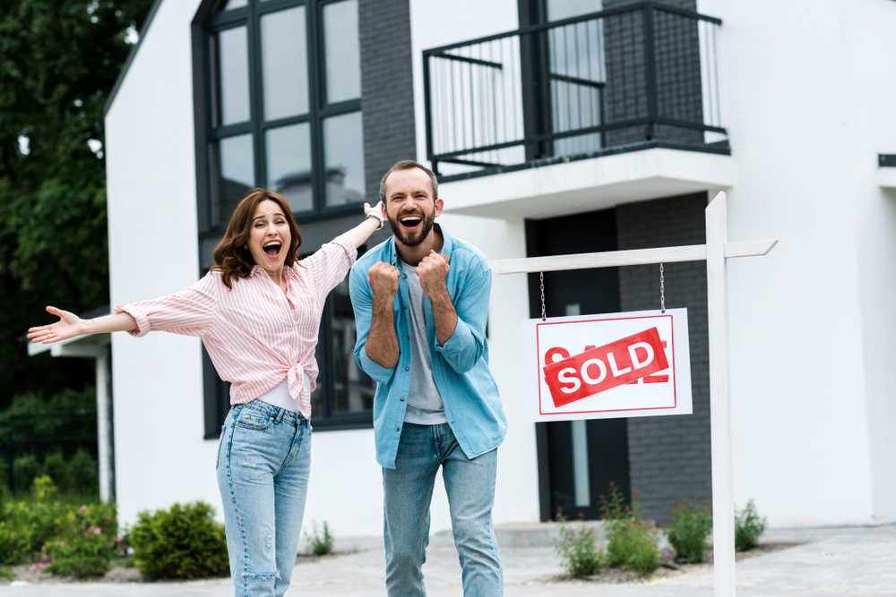 Cheerful,Man,And,Woman,Celebrating,Near,House,And,Board,With