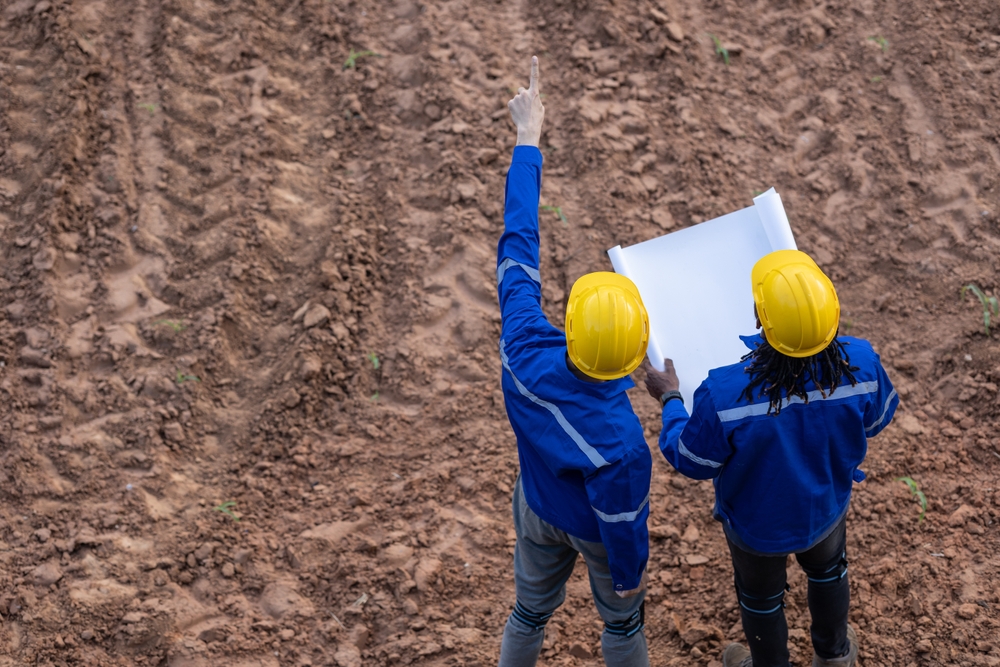 Land,Surveyor,Team,Standing,Working,Together,At,Construction,Field,Consult